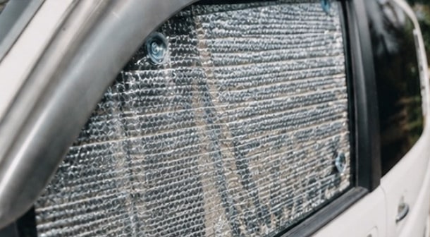 The same van window with a standard thermal blind: reflective silver foil showing